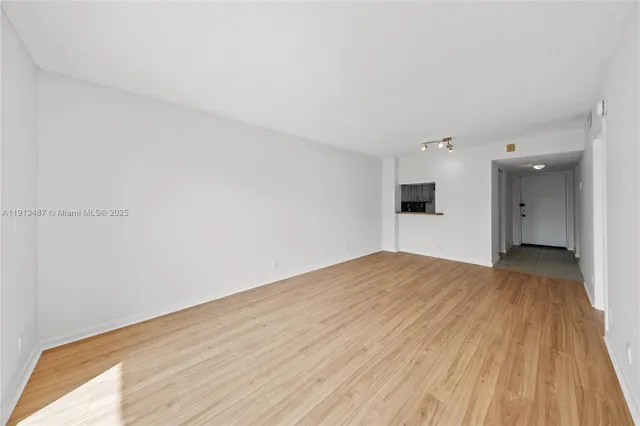 a view of empty room with wooden floor and a window