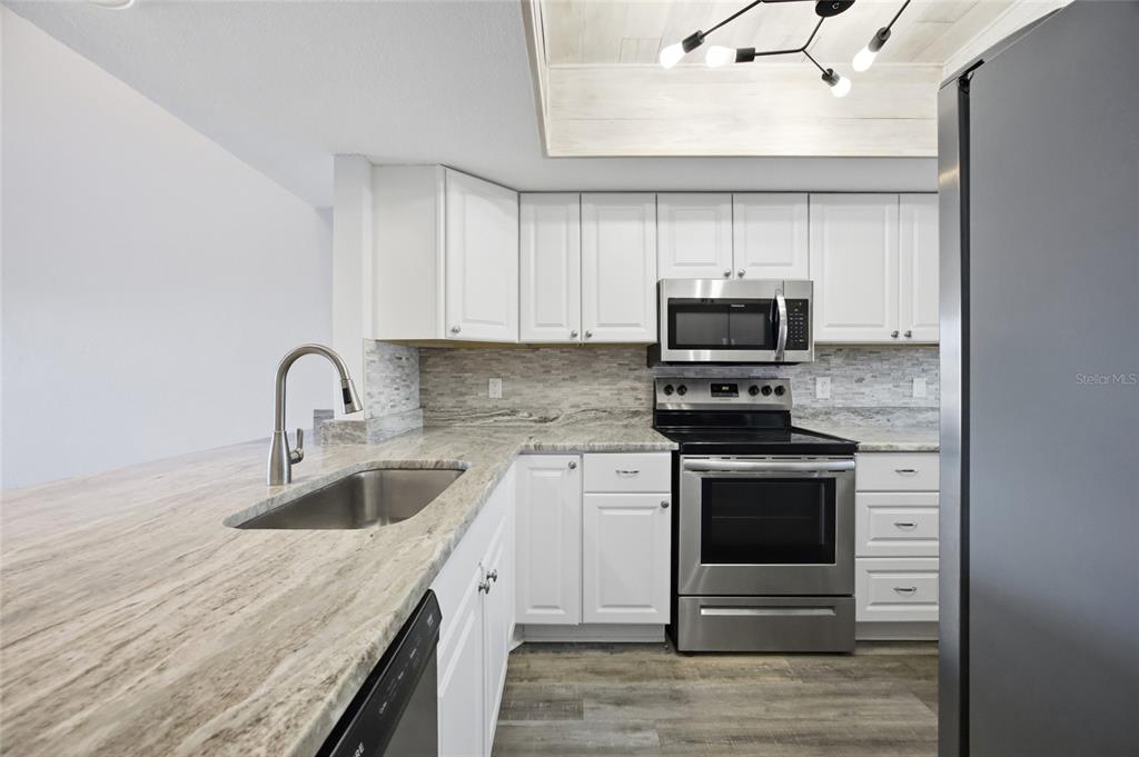 8210 Aquila Street, Unit 227 Port Richey, FL 34668 - Photo 16 of 68 a kitchen with granite countertop a sink stainless steel appliances and cabinets