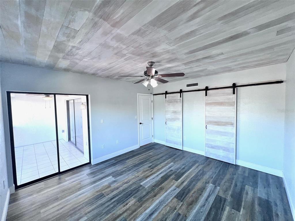 8210 Aquila Street, Unit 227 Port Richey, FL 34668 - Photo 30 of 68 an empty room with wooden floor fan and windows