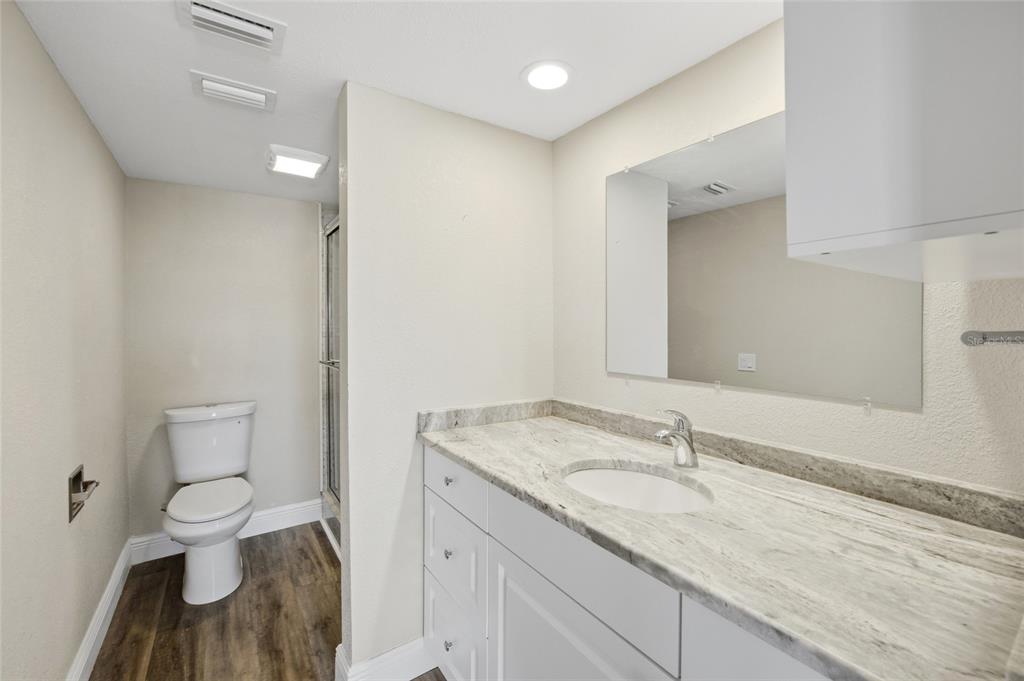 8210 Aquila Street, Unit 227 Port Richey, FL 34668 - Photo 33 of 68 a bathroom with a granite countertop sink a toilet and a mirror