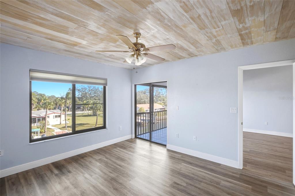 8210 Aquila Street, Unit 227 Port Richey, FL 34668 - Photo 36 of 68 an empty room with wooden floor chandelier fan and windows