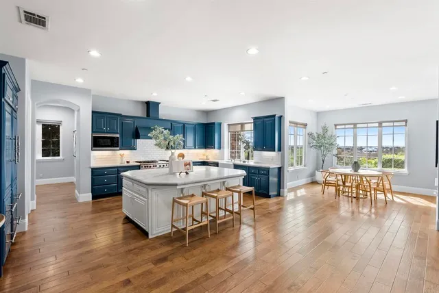 a living room with stainless steel appliances kitchen island furniture and a wooden floor