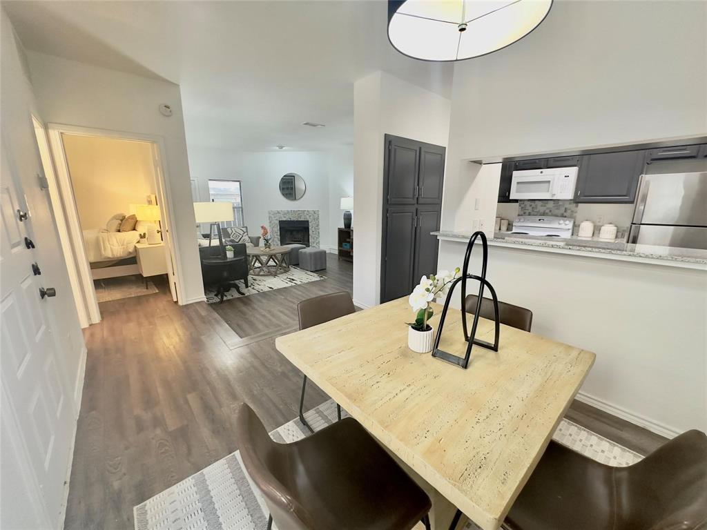 7340 Skillman Street, Unit 405 Dallas, TX 75231 - Photo 5 of 18 Dining area with wood-finish flooring, featuring a breakfast bar with a stone-look countertop and mosaic tile backsplash