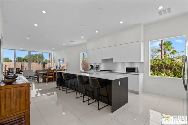a large kitchen with kitchen island a sink a stove a center island a dining table and chairs