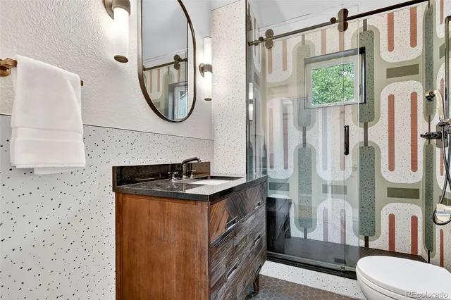 a bathroom with a granite countertop toilet sink and mirror