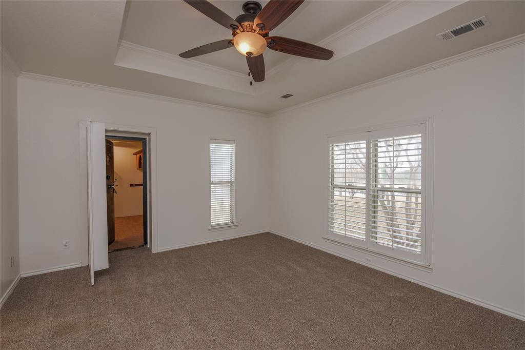 364 Parker Road, Unit A Van Alstyne, TX 75495 - Photo 19 of 39 Spacious downstair primary bedroom featuring a beautiful view of the pond, a tray ceiling, ceiling fan with integrated lighting, carpeted flooring, and window treatments
