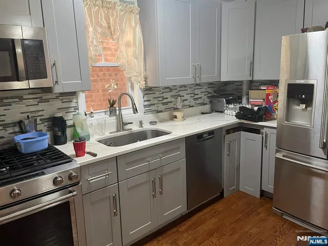a kitchen with stainless steel appliances a sink cabinets and a window