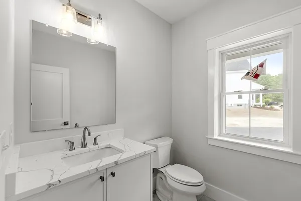 a bathroom with a granite countertop sink a toilet and a window