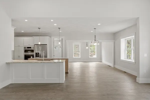 a large kitchen with stainless steel appliances kitchen island a large counter top and a wooden floor