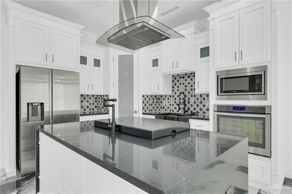 1315 Thompson Road Mission, TX 78573 - Photo 10 of 38 Kitchen with a center island, appliances with stainless steel finishes, island range hood, and dark stone counters
