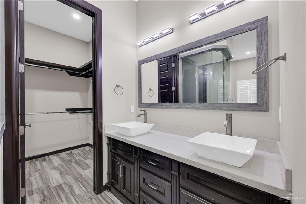1315 Thompson Road Mission, TX 78573 - Photo 22 of 38 Bathroom featuring double vanity, light wood-type flooring, a walk in closet, recessed lighting, and a shower stall