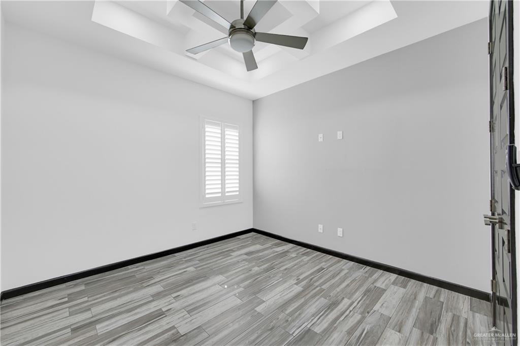 1315 Thompson Road Mission, TX 78573 - Photo 27 of 38 Empty room featuring a raised ceiling, light wood finished floors, and a ceiling fan