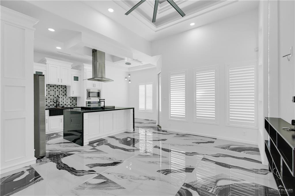 1315 Thompson Road Mission, TX 78573 - Photo 8 of 38 Kitchen with white cabinets, light marble finish floors, exhaust hood, a center island, and dark countertops