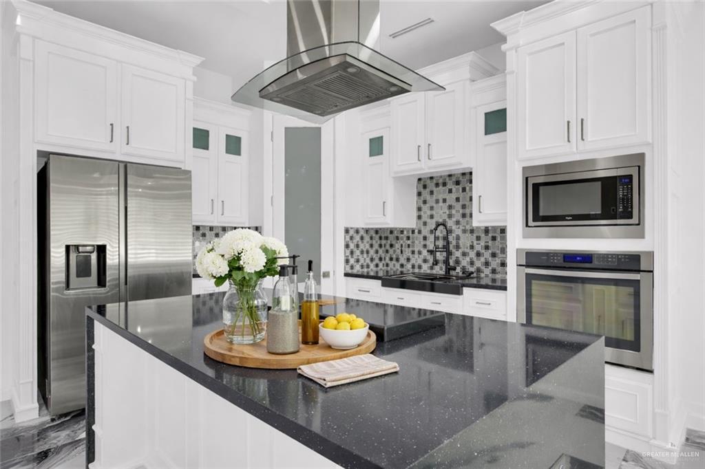 1315 Thompson Road Mission, TX 78573 - Photo 9 of 38 Kitchen with stainless steel appliances, exhaust hood, white cabinetry, dark stone counters, and a spacious island