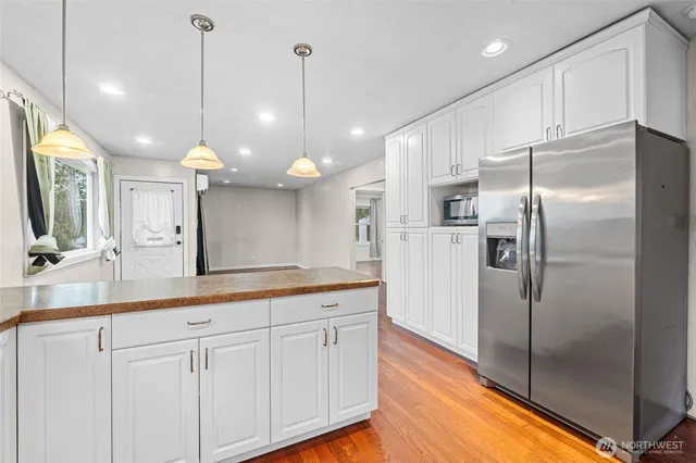 a kitchen with kitchen island a counter top space stainless steel appliances and wooden floor
