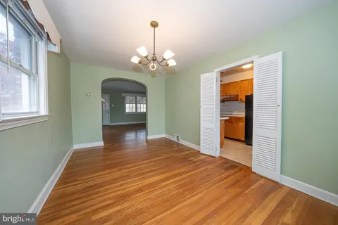 a view of an empty room with window and wooden floor