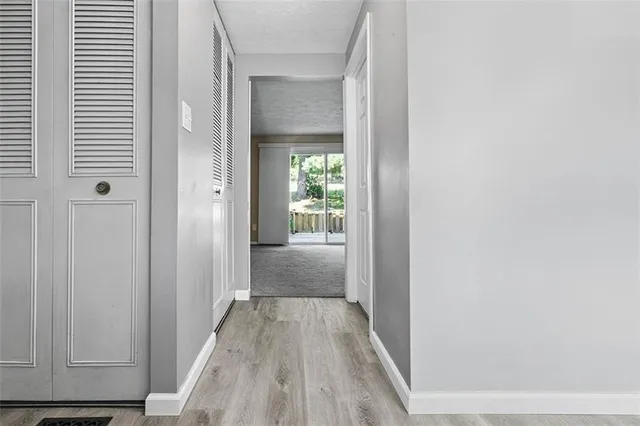 a view of a hallway with wooden floor and a bathroom