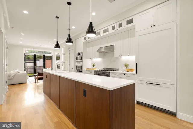 a large kitchen with stainless steel appliances kitchen island granite countertop a large counter top a sink a stove and a refrigerator