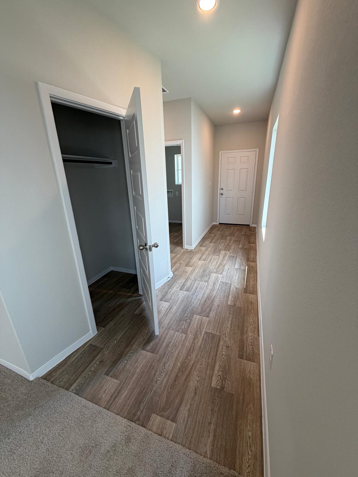 2612 Towy Road Manor, TX 78653 - Photo 29 of 35 A well-lit hallway with modern wood-look flooring connects various spaces within the residence.