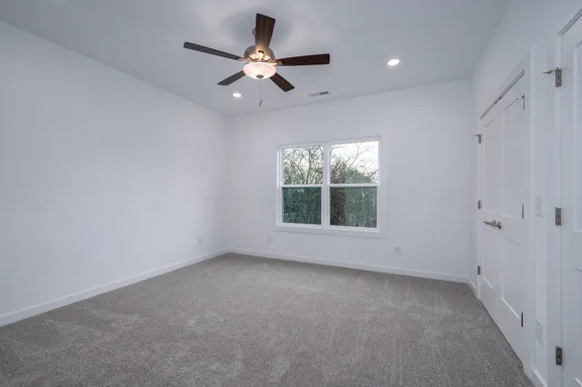 an empty room with windows and fan