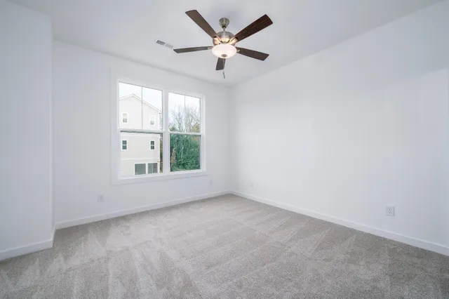 an empty room with windows and ceiling fan