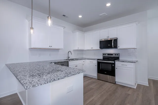 a kitchen with kitchen island granite countertop stainless steel appliances a stove sink microwave and cabinets