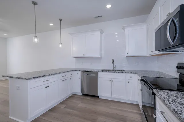 a kitchen with granite countertop a sink a stove and cabinets