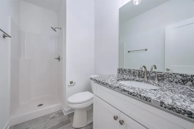 a bathroom with a granite countertop sink a toilet and shower