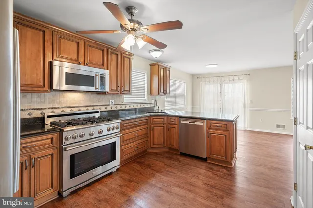 a kitchen with granite countertop wooden cabinets stainless steel appliances and a window