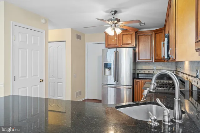 a kitchen with stainless steel appliances granite countertop a refrigerator a stove and a sink