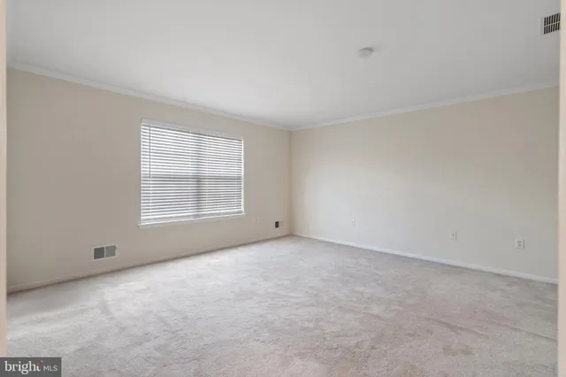 a view of an empty room with closet and a window