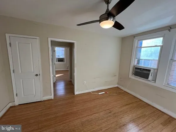 an empty room with wooden floor cabinet and windows