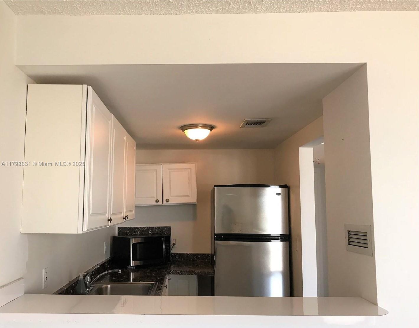 1100 Alton Road, Unit 3D Miami Beach, FL 33139 - Photo 7 of 14 a kitchen with stainless steel appliances granite countertop a refrigerator a stove a sink and white cabinets with wooden floor