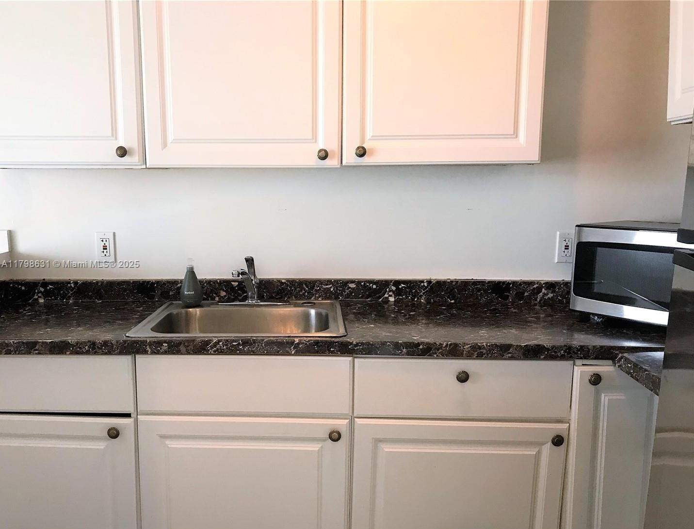 1100 Alton Road, Unit 3D Miami Beach, FL 33139 - Photo 8 of 14 a kitchen with granite countertop a sink and a white cabinets