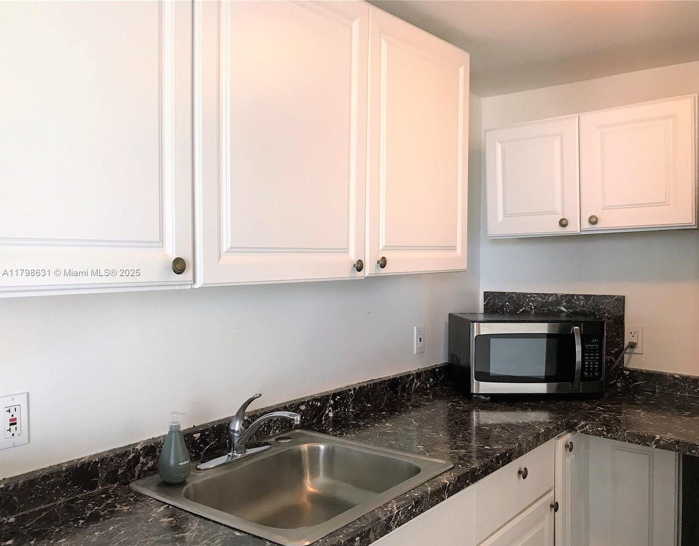 1100 Alton Road, Unit 3D Miami Beach, FL 33139 - Photo 9 of 14 a kitchen with granite countertop white cabinets and a sink