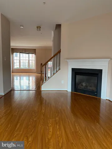 an empty room with wooden floor fireplace and windows