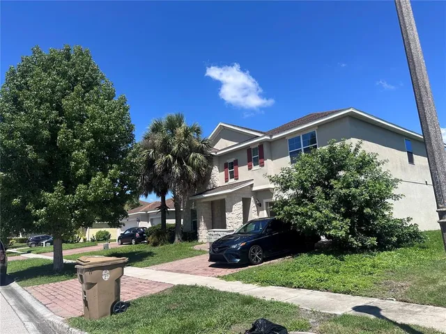 a front view of a house with garden and trees