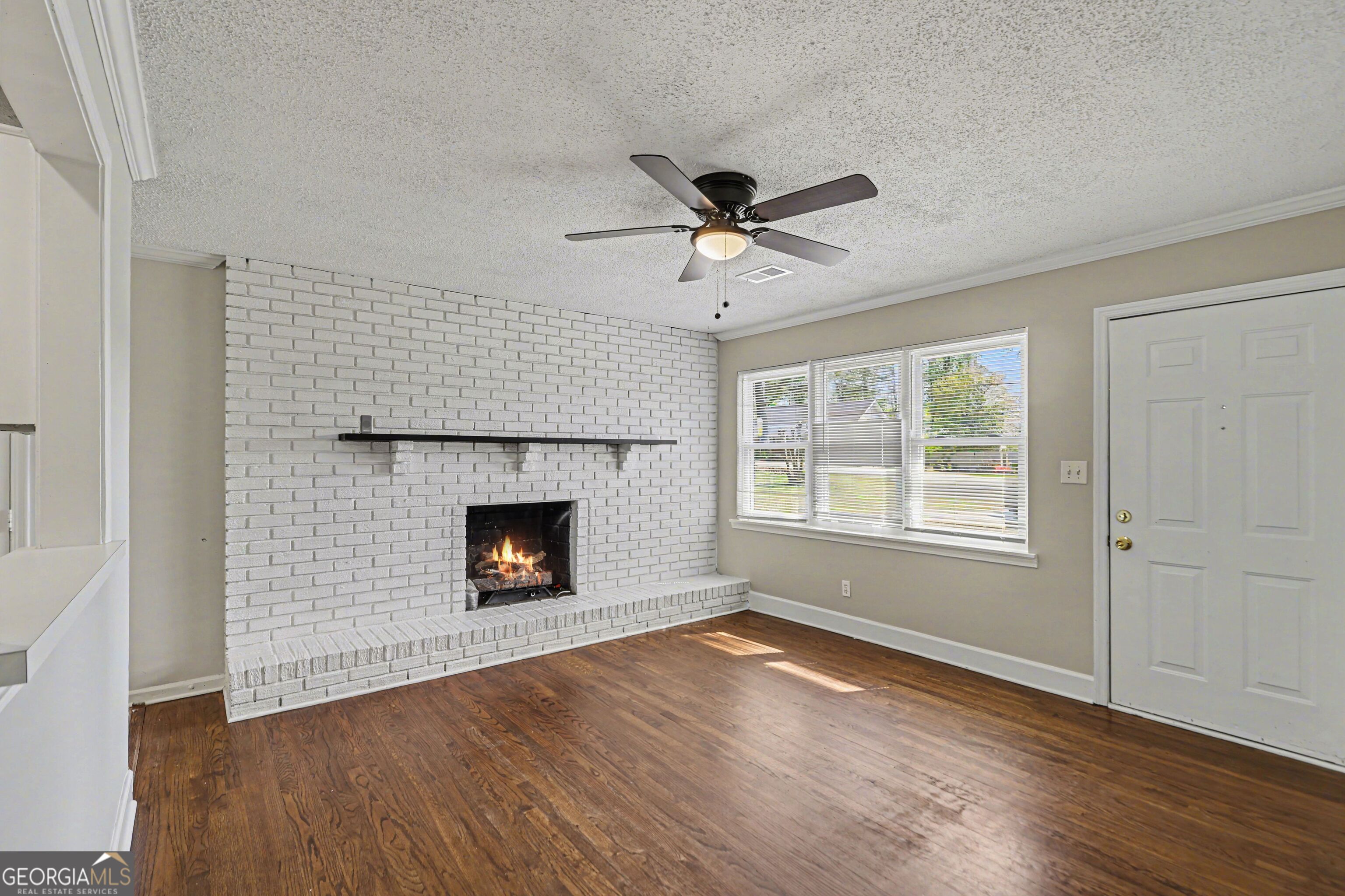 3670 Goodwin Road Austell, GA 30106 - Photo 5 of 16 an empty room with wooden floor fireplace and windows