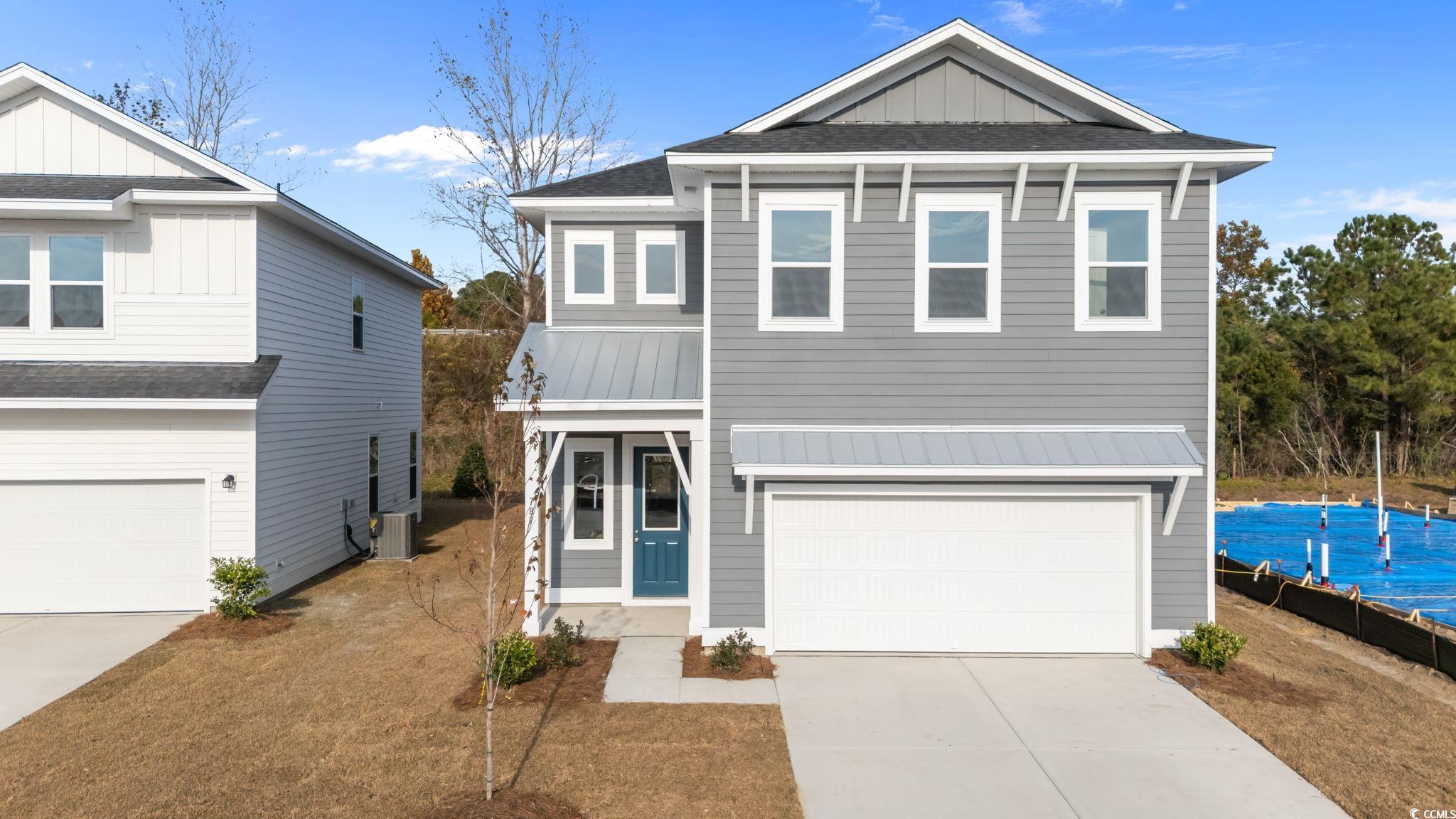 View of front facade with an attached garage, driveway, and board and batten siding