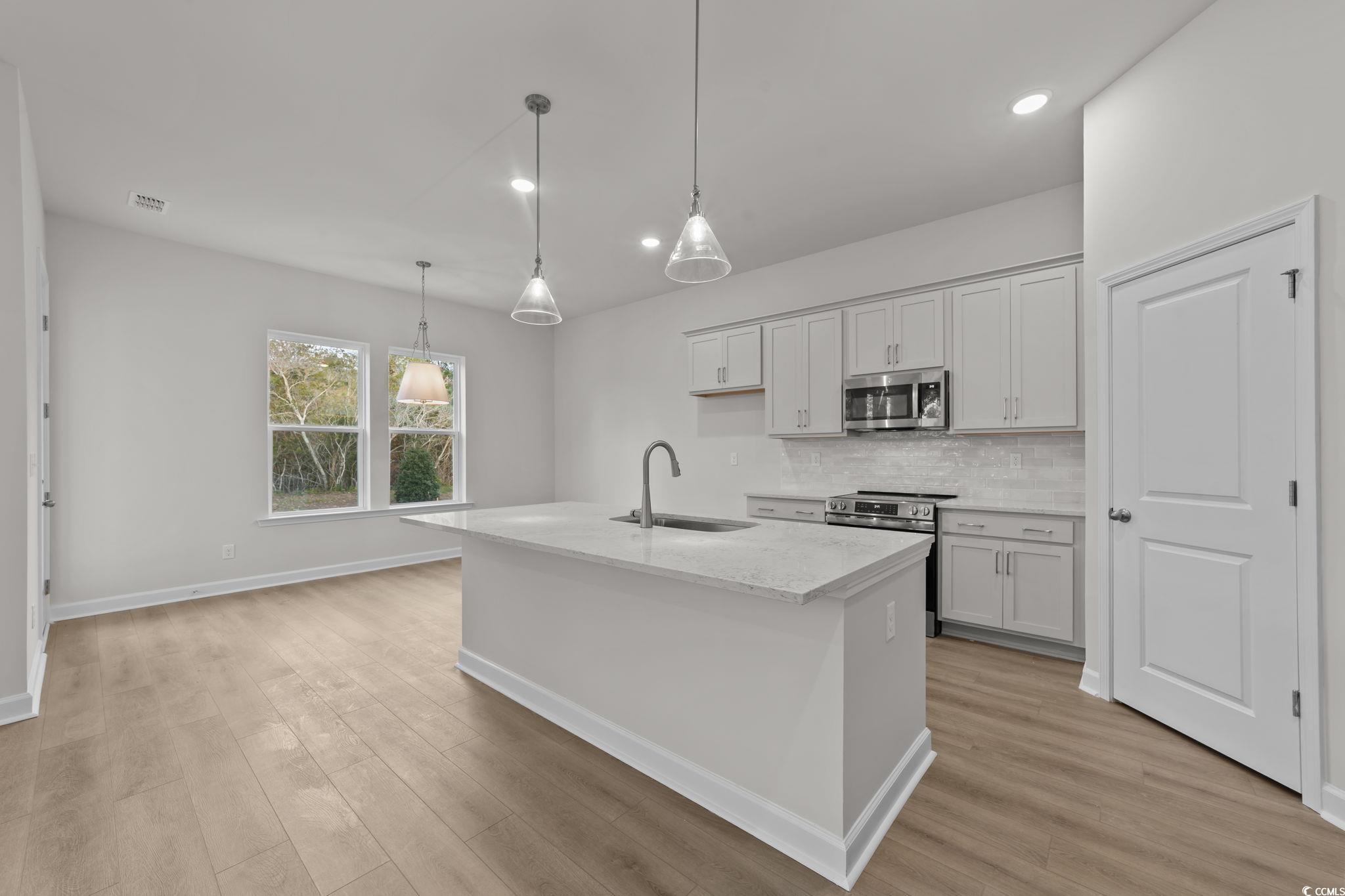 787 Ebb Tide Road Little River, SC 29566 - Photo 11 of 32 Kitchen featuring recessed lighting, an island with sink, light stone countertops, stainless steel appliances, and decorative backsplash