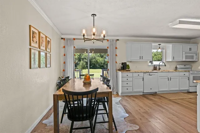 a kitchen with stainless steel appliances granite countertop a dining table chairs and white cabinets