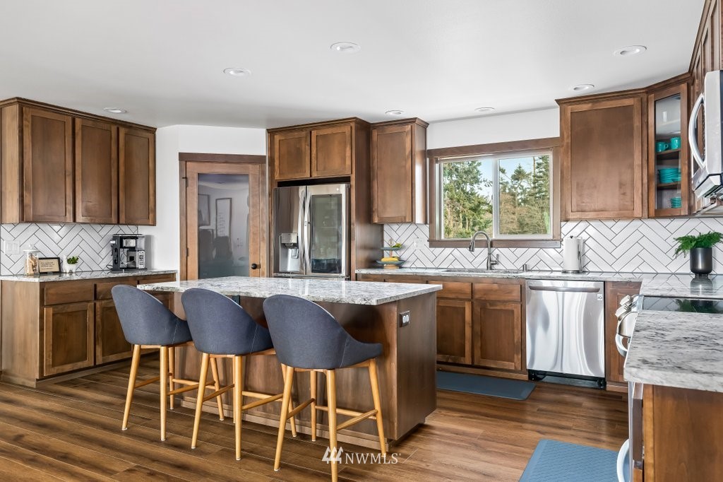 1471 North View Road Oak Harbor, WA 98277 - Photo 8 of 38 a kitchen with stainless steel appliances granite countertop wooden floor and chairs