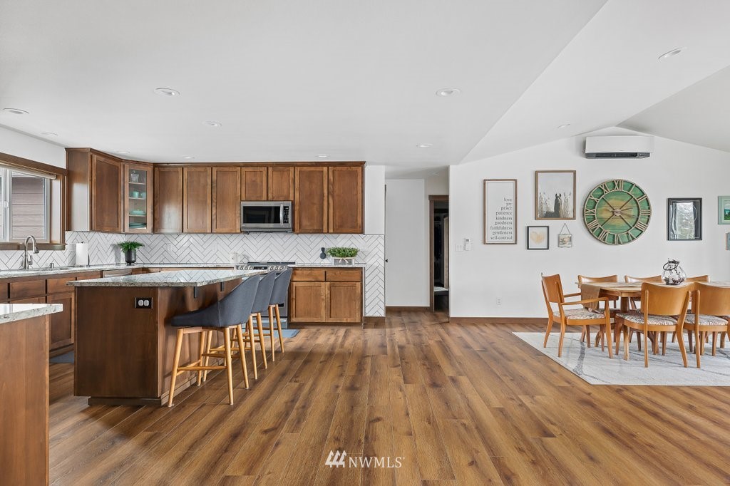 1471 North View Road Oak Harbor, WA 98277 - Photo 9 of 38 a kitchen with stainless steel appliances granite countertop a refrigerator a stove top oven a dining table and chairs with wooden floor