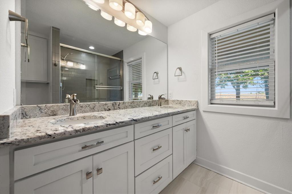 917 Goodwyn Road Italy, TX 76651 - Photo 22 of 40 Double vanity with light-toned countertop, dual undermount sinks, and chrome faucets