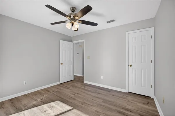 an empty room with wooden floor and ceiling fan