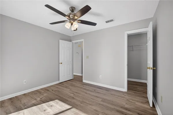 an empty room with wooden floor and a ceiling fan