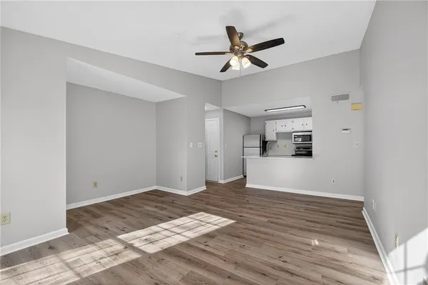 a view of empty room with wooden floor and ceiling fan