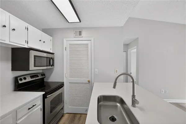 a kitchen with stainless steel appliances granite countertop a sink a stove a refrigerator a window and white cabinets