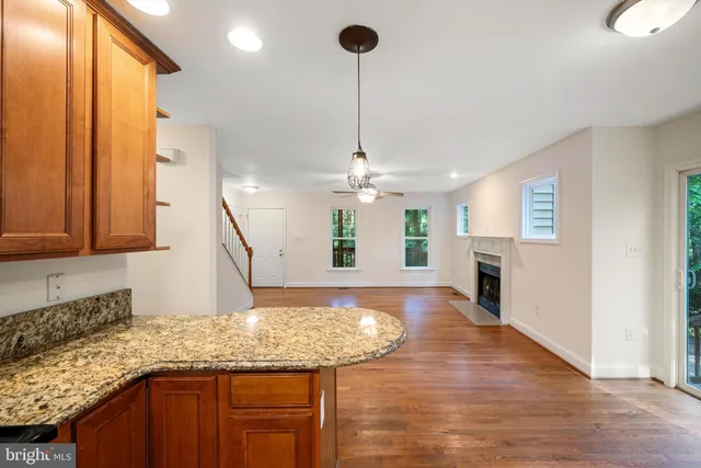 a kitchen with kitchen island granite countertop wooden floor and a refrigerator