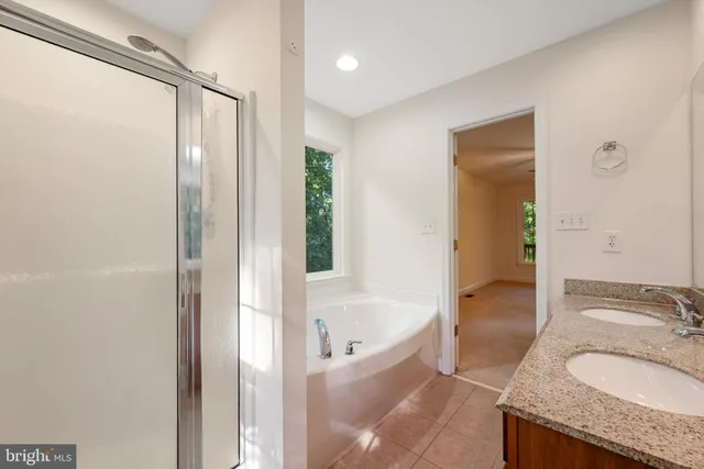 a bathroom with a granite countertop tub sink and mirror